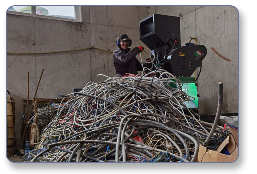 Eine Kabelrecyclinganlage mit einem Haufen Kabel und einerm Arbeiter bei der Bedienung